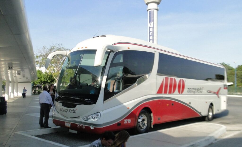 "Comfortable bus traveling to Tulum, surrounded by people.