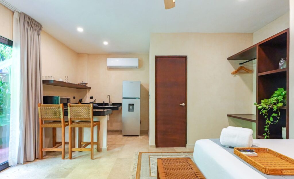 Habitación de hotel con cocineta, cama y una terraza 