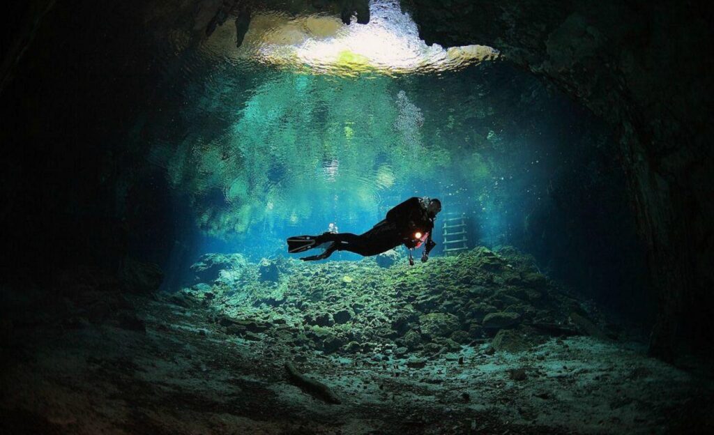 Buzo nadando en las profundidades del gran cenote